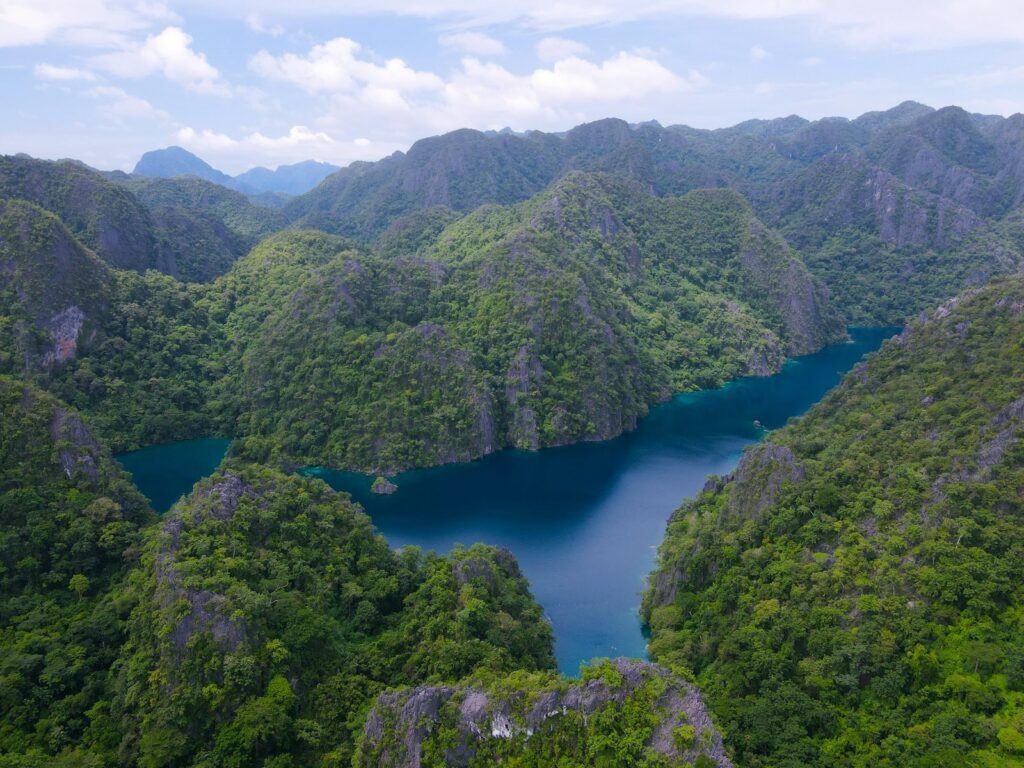 Laguna biru di antara perbukitan karst hijau yang tenang