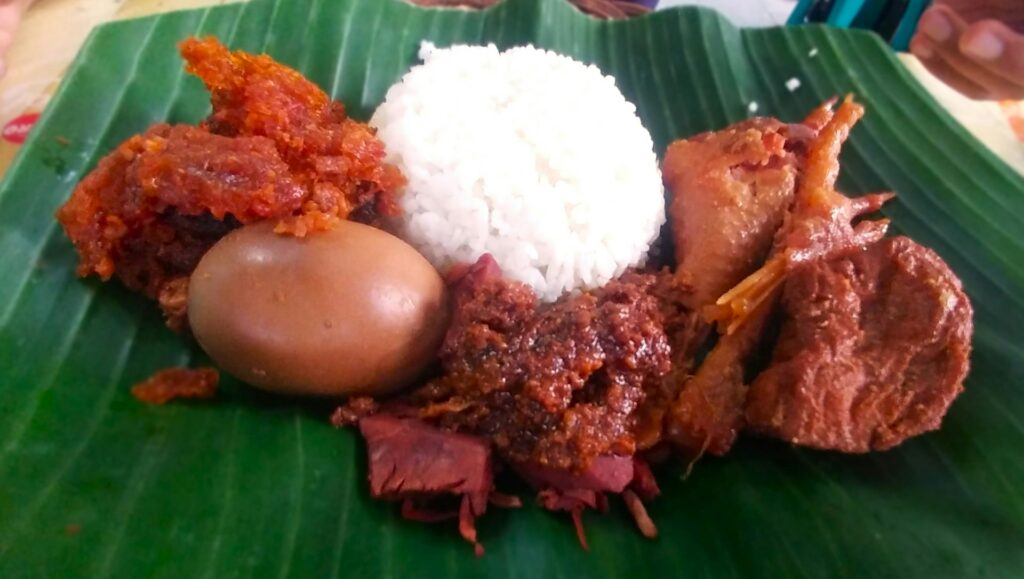 Nasi gudeg kering dengan areh, krecek, telur, dan ayam kampung di atas daun pisang