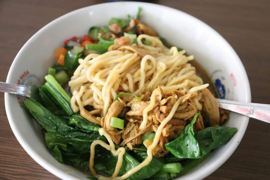 Semangkuk bakmi Mie Lampung Pak Kardi Semarang dengan topping ayam dan sayuran hijau
