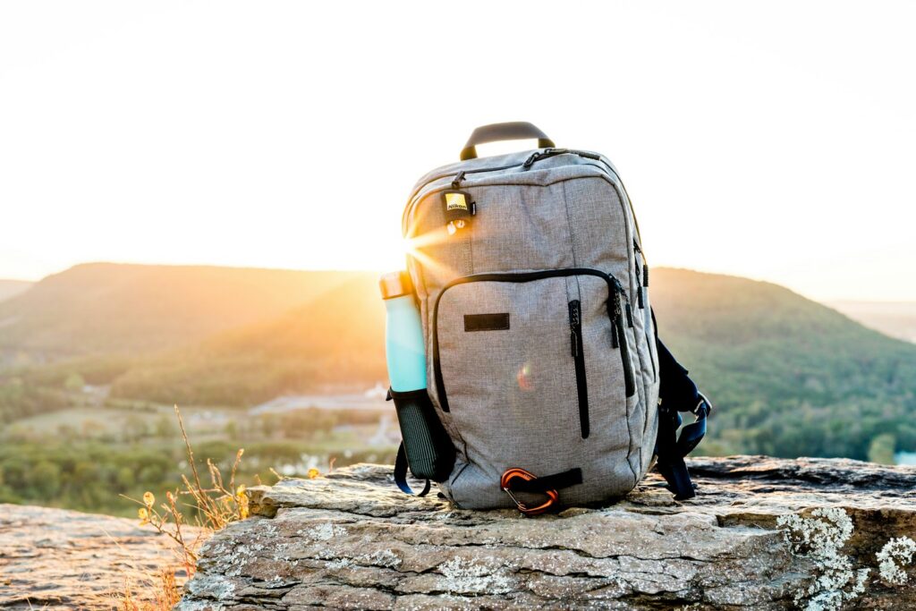 Ransel dan botol minum di atas batu saat matahari terbenam
