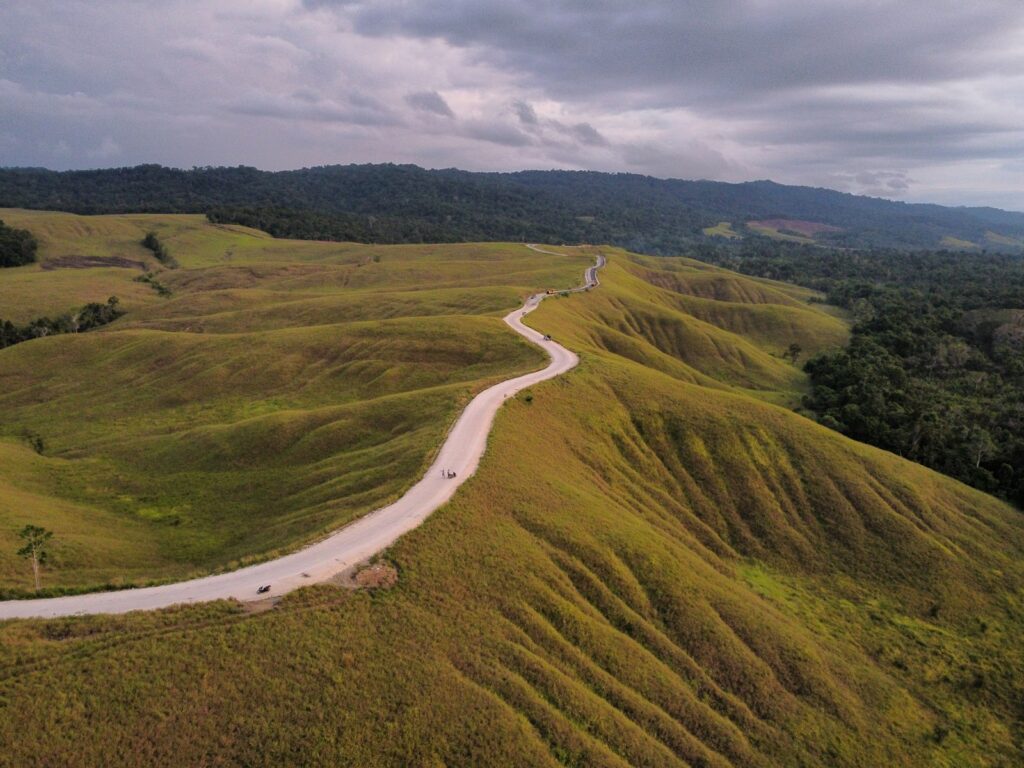 Jalan berkelok melewati perbukitan hijau di Lombok