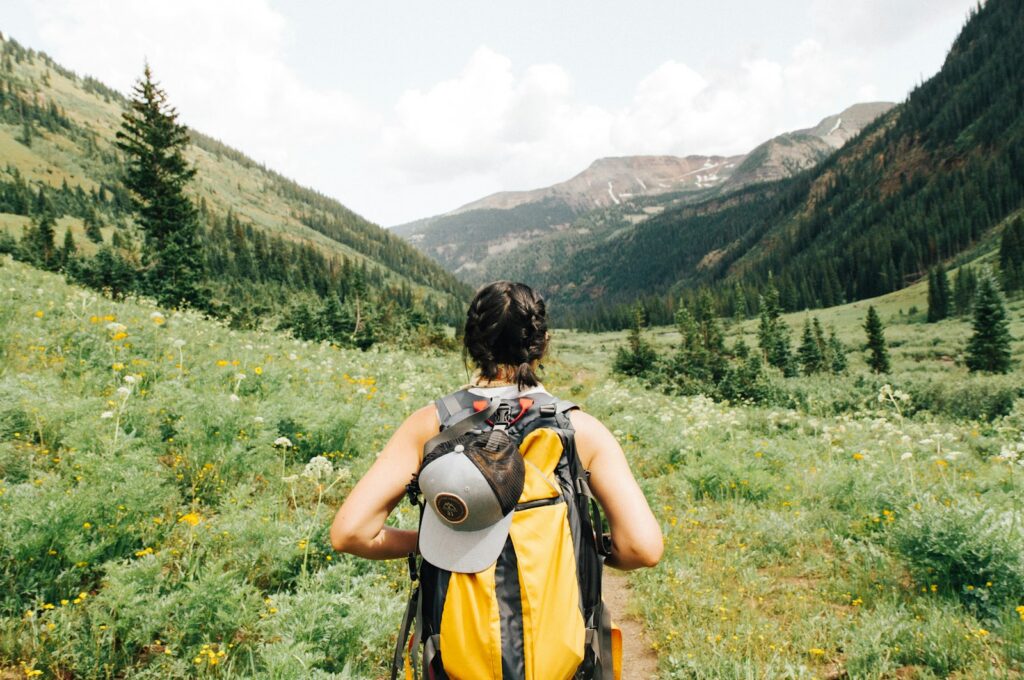 Solo traveler dengan ransel berjalan menyusuri jalur alam